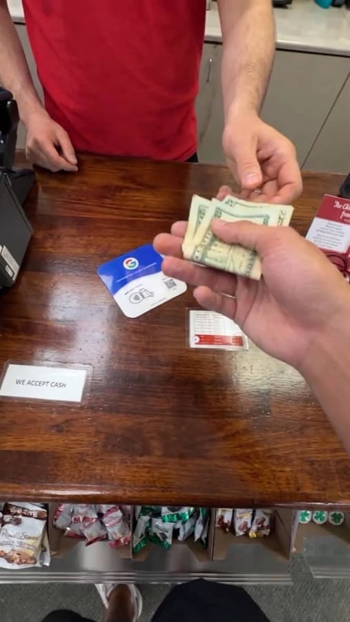 A Google review card on a shop counter, tapped with a phone (2)